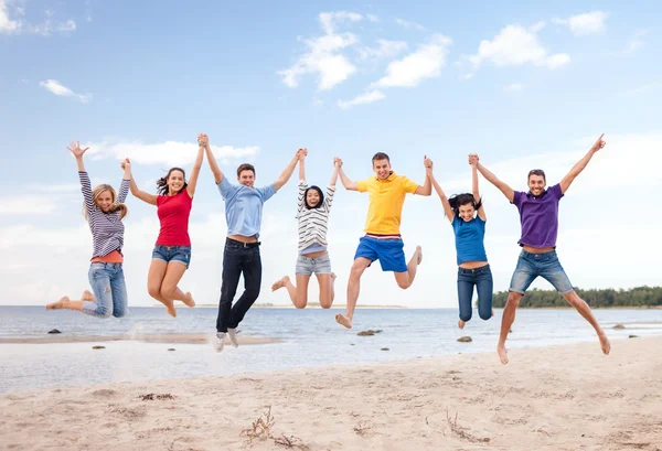 Groep vrienden springen op het strand — Stockfoto