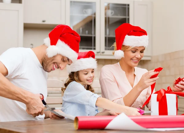 Familia sonriente en sombreros de Santa Helper con caja de regalo — Foto de Stock