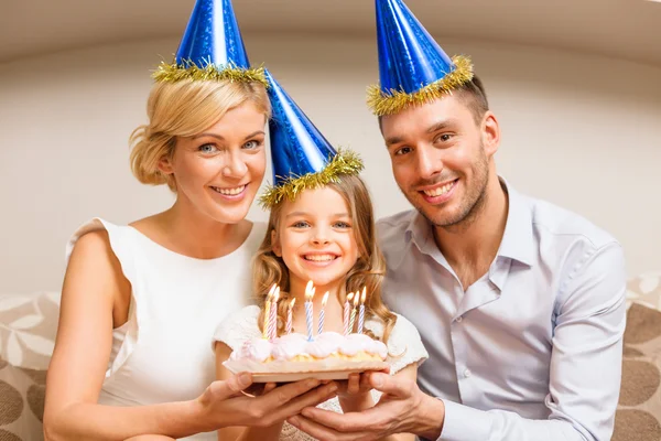 Usmívající se rodina v modré klobouky s dortem — Stock fotografie