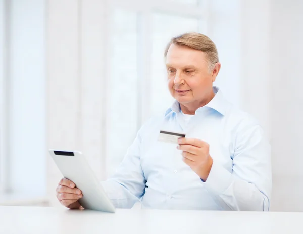Старик с планшетным ПК и кредитной картой дома — стоковое фото