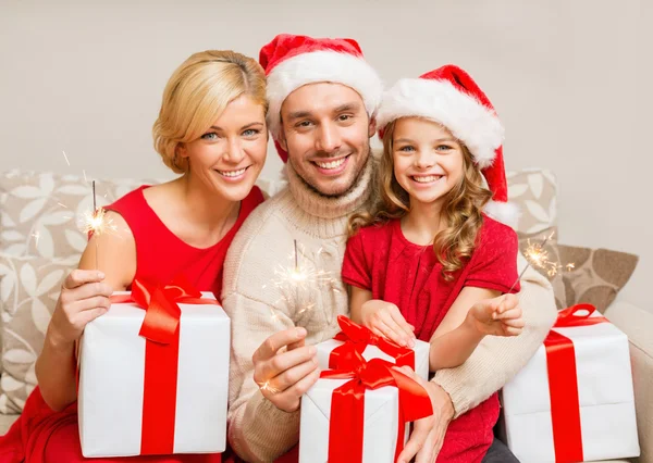 Smiling family holding gift boxes and sparkles — Stock Photo, Image