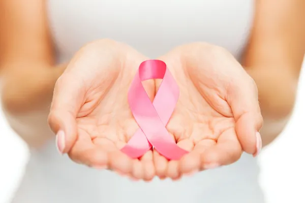 Mani che tengono il nastro rosa della consapevolezza del cancro al seno — Foto Stock