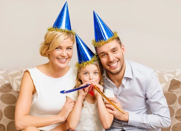 Sonriente familia en sombreros azules soplando cuernos favor — Foto de Stock