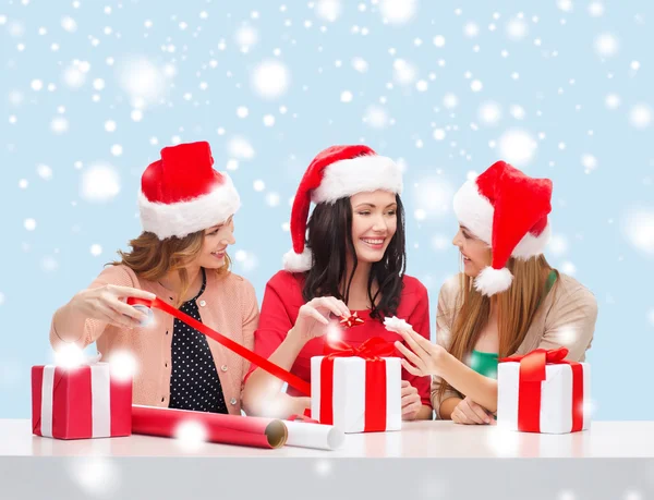 Donne sorridenti in cappelli di Babbo Natale con scatole regalo — Foto Stock