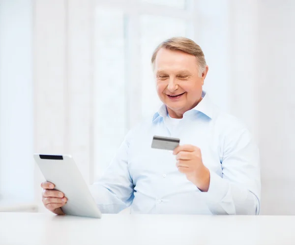 Старик с планшетным ПК и кредитной картой дома — стоковое фото
