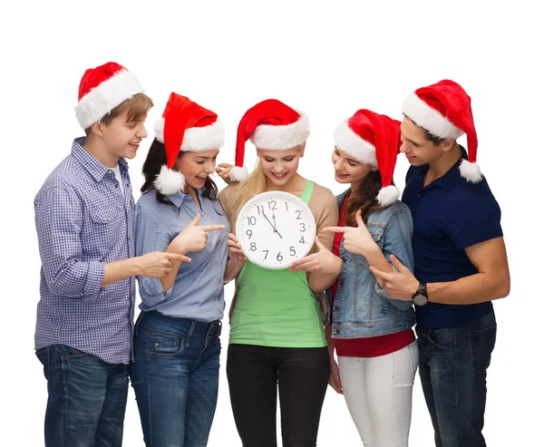 Groep lachende studenten met klok weergegeven: 12 — Stockfoto