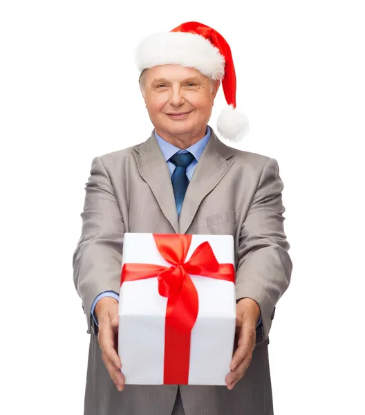 Sorrindo homem de terno e chapéu de Papai Noel ajudante com presente — Fotografia de Stock