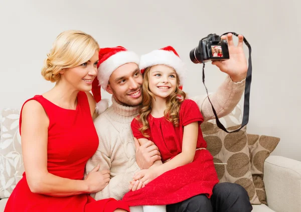 Sonriente familia en santa helper sombreros tomando fotos —  Fotos de Stock