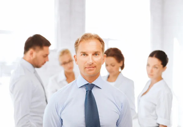 Businessman in office with group on the back — Stock Photo, Image