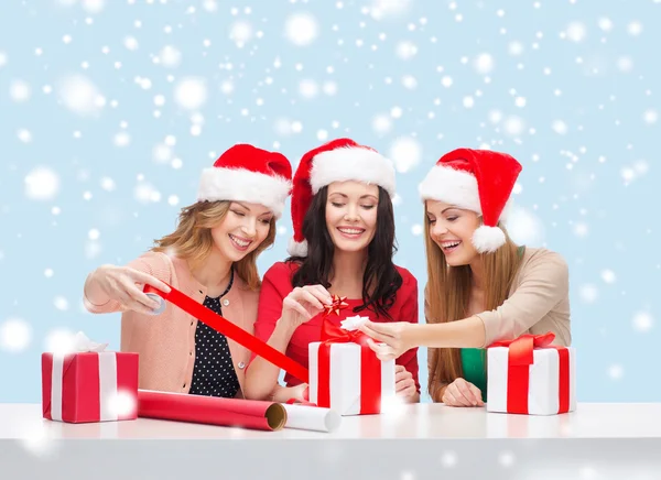 Femmes souriantes dans des chapeaux d'aide de père Noël avec des boîtes-cadeaux — Photo