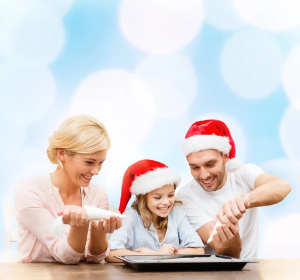 Familia feliz en sombreros de Santa Helper haciendo galletas — Foto de Stock