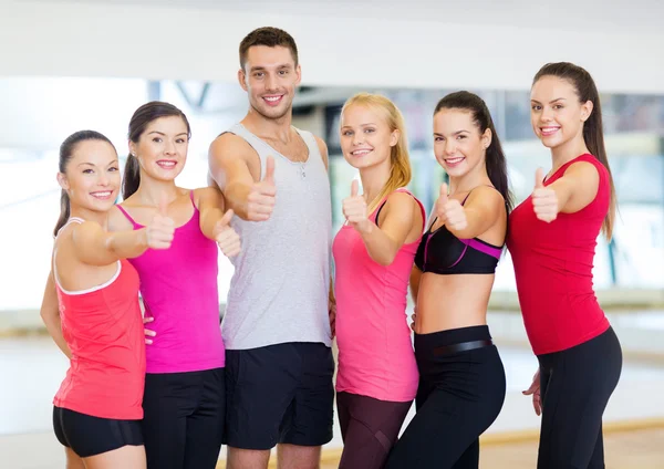 Grupp människor i gymmet visar tummen — Stockfoto