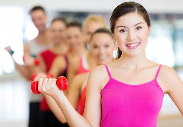 Groep lachende mensen met halters in de sportschool — Stockfoto