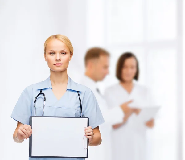 Uśmiechnięta kobieta lekarz lub pielęgniarka z sclipboard — Zdjęcie stockowe