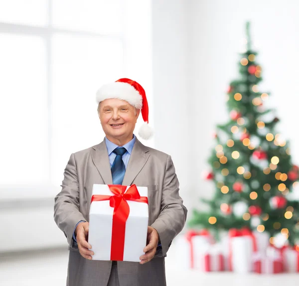 Lächelnder Mann im Anzug und Weihnachtsmannmütze mit Geschenk — Stockfoto