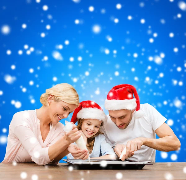 Glückliche Familie mit Weihnachtsmannmützen, die Plätzchen backen — Stockfoto