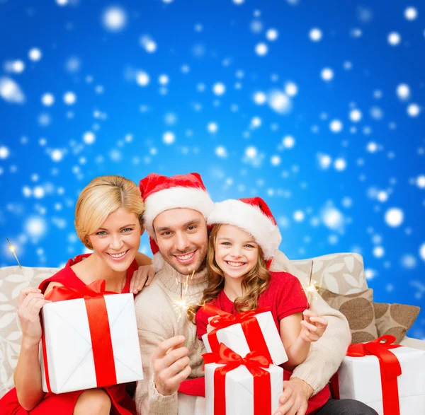 Familia sonriente sosteniendo cajas de regalo y destellos — Foto de Stock