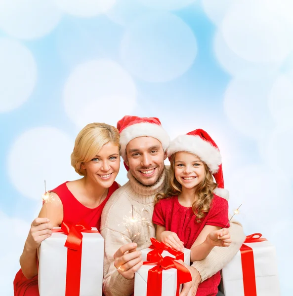 Familia sonriente sosteniendo cajas de regalo y destellos —  Fotos de Stock