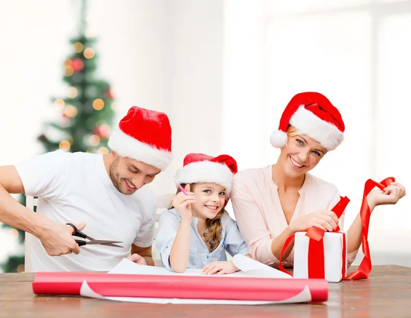 Familia sonriente en sombreros de Santa Helper con caja de regalo — Foto de Stock