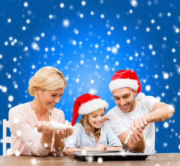 Glückliche Familie mit Weihnachtsmannmützen, die Plätzchen backen — Stockfoto