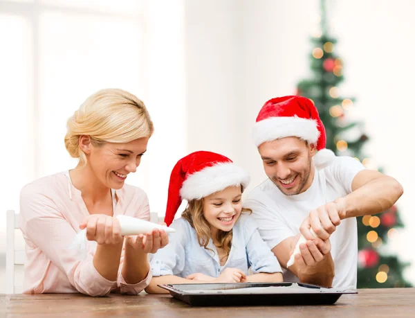 Familia feliz en sombreros de Santa Helper haciendo galletas — Foto de Stock