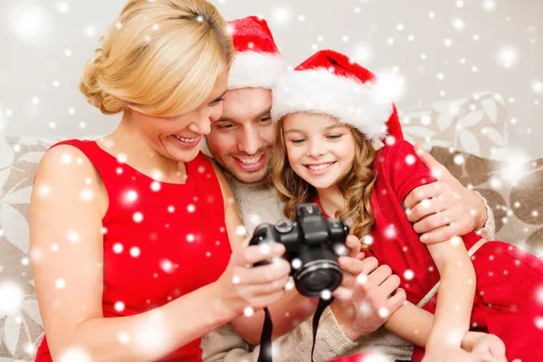 Famille dans santa helper chapeaux regardant pictires — Photo