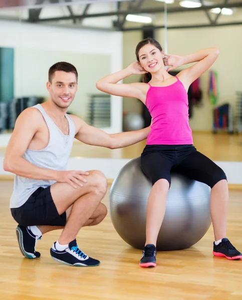 Treinador masculino com mulher fazendo crunches na bola — Fotografia de Stock