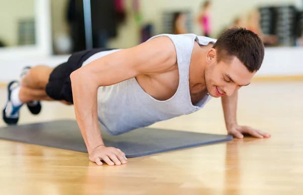 Glimlachende man doen push-ups in de sportschool — Stockfoto