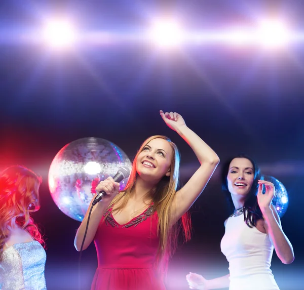 Tre leende kvinnor dansa och sjunga karaoke — Stockfoto