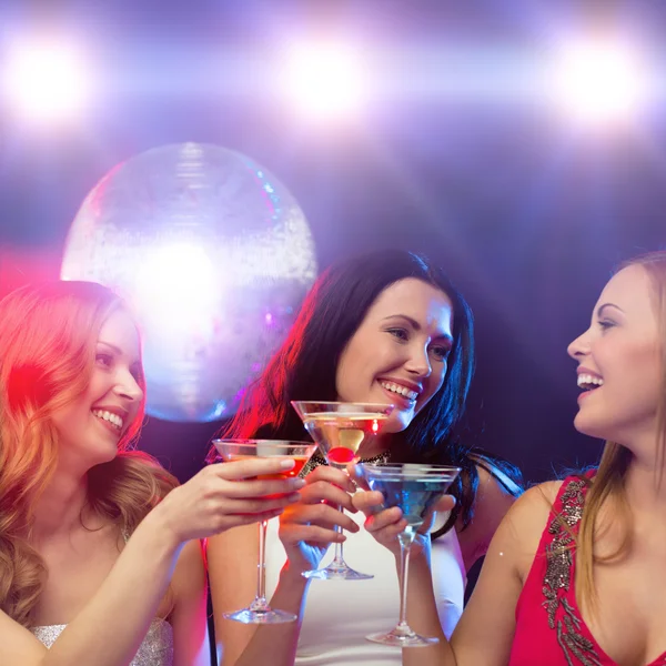 Drie glimlachende vrouwen met cocktails en disco bal — Stockfoto