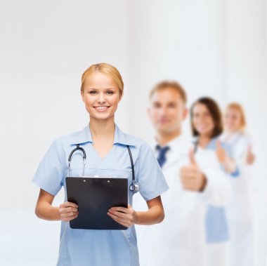 Smiling female doctor or nurse with clipboard clipart