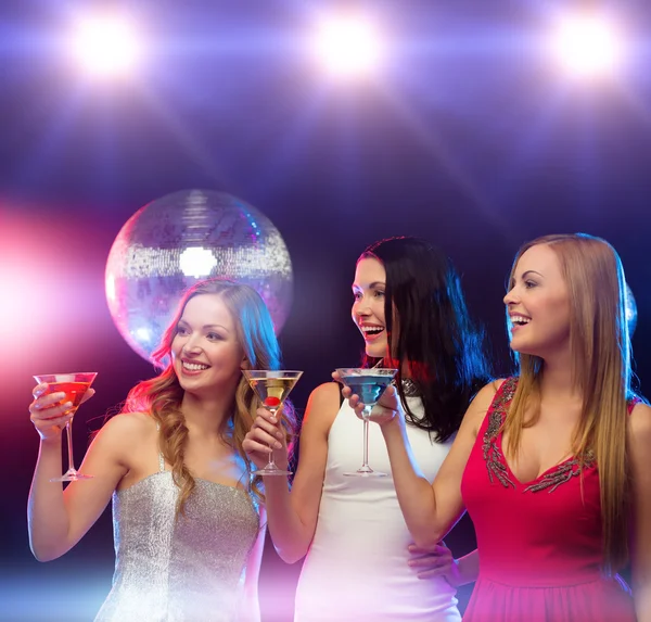 Drie glimlachende vrouwen met cocktails en disco bal — Stockfoto