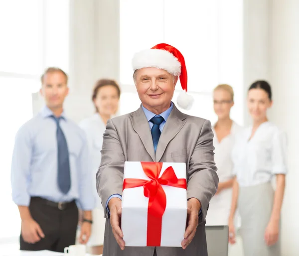 Sorrindo homem de terno e chapéu de Papai Noel ajudante com presente — Fotografia de Stock