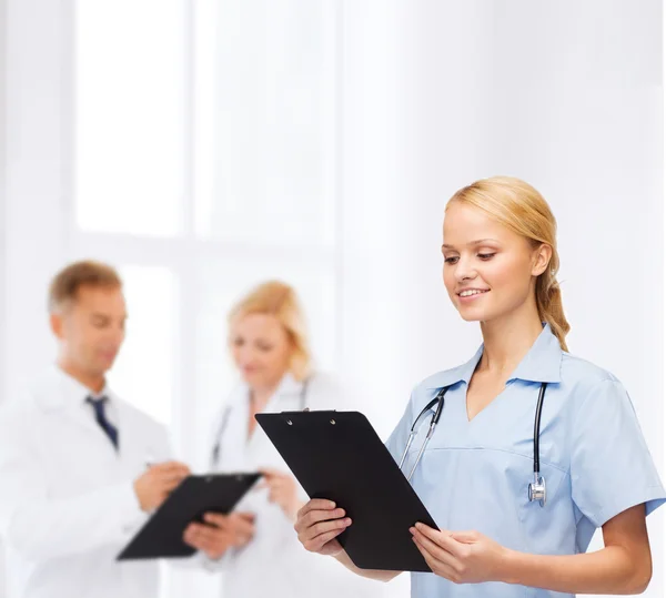 Médico o enfermera sonriente con portapapeles — Foto de Stock