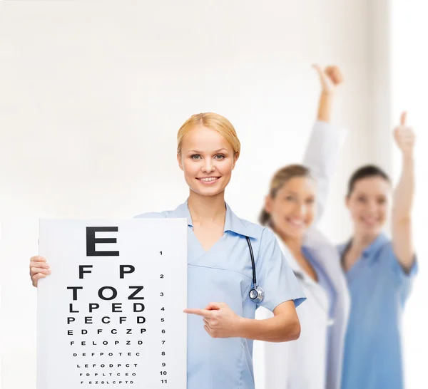 Smiling female doctor or nurse with eye chart — Stock Photo, Image