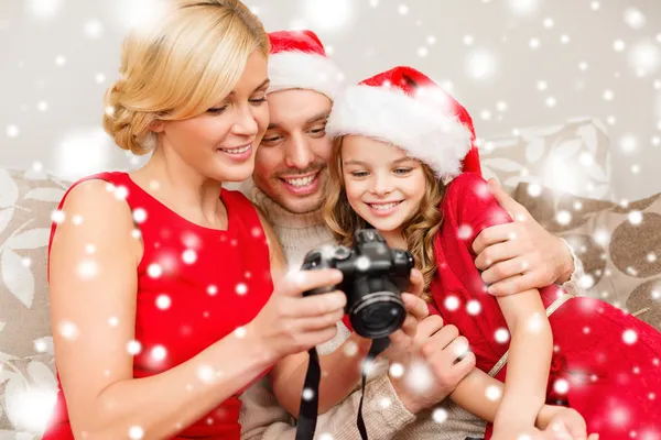 Familie mit Weihnachtsmann-Helferhüten schaut sich Bilder an — Stockfoto