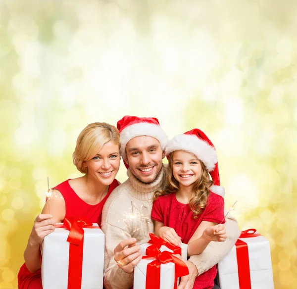 Familia sonriente sosteniendo cajas de regalo y destellos —  Fotos de Stock