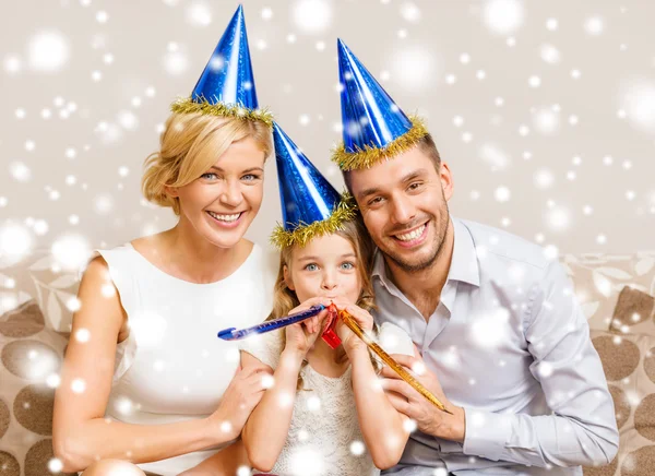 Sonriente familia en sombreros azules soplando cuernos favor — Foto de Stock