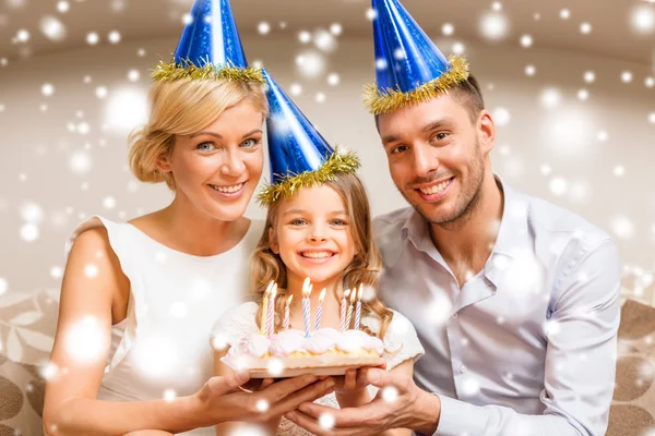 微笑在蓝色的帽子与蛋糕的家庭 — 图库照片