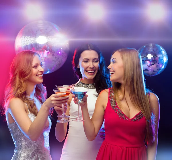 Drie glimlachende vrouwen met cocktails en disco bal — Stockfoto