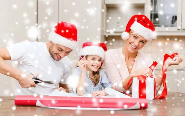 Famille souriante dans santa chapeaux d'aide avec boîte cadeau — Photo