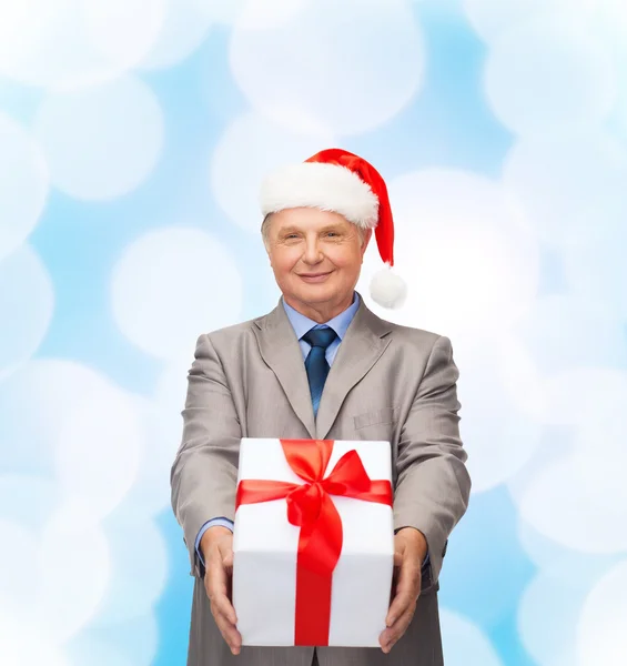 Sorrindo homem de terno e chapéu de Papai Noel ajudante com presente — Fotografia de Stock