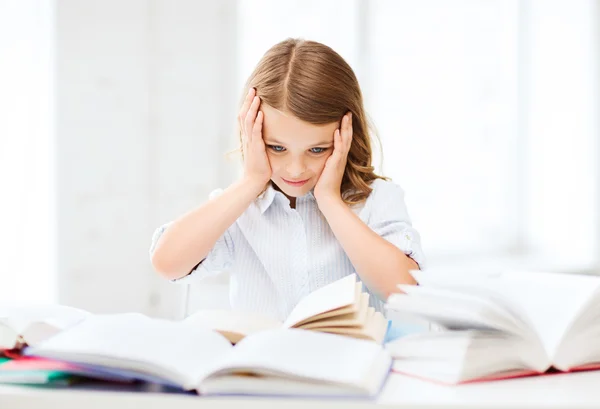 Söt flicka med många böcker i skolan — Stockfoto