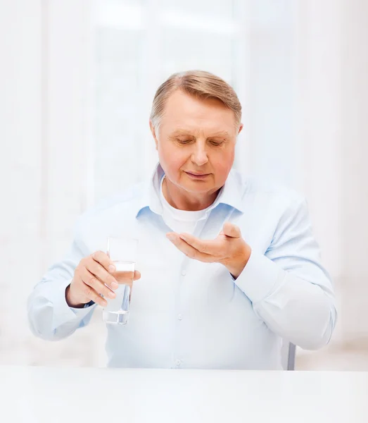 Old man with pills ang glass of water — Stock Photo, Image