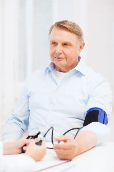 Médica ou enfermeira que mede a pressão arterial — Fotografia de Stock