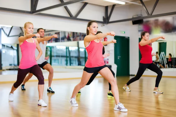 Grupo de personas sonrientes haciendo ejercicio en el gimnasio — Foto de Stock