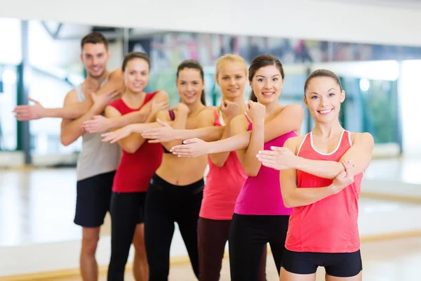 Group of smiling people stretching in the gym Royalty Free Stock Images