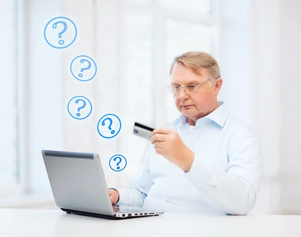 Oude man met laptop en een creditcard bij u thuis — Stockfoto