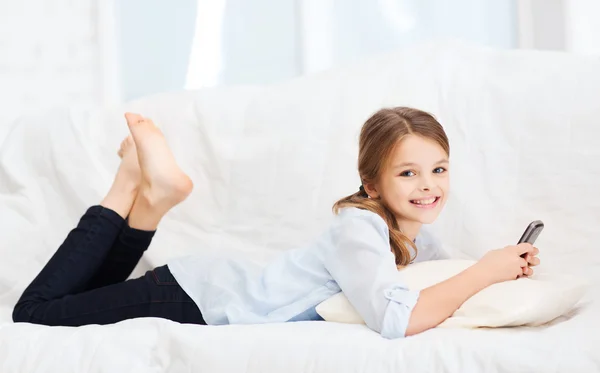 Menina sorridente com smartphone em casa — Fotografia de Stock