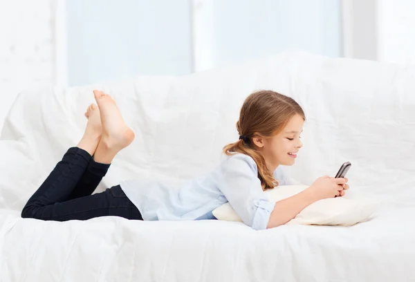 Lachende meisje met smartphone thuis — Stockfoto